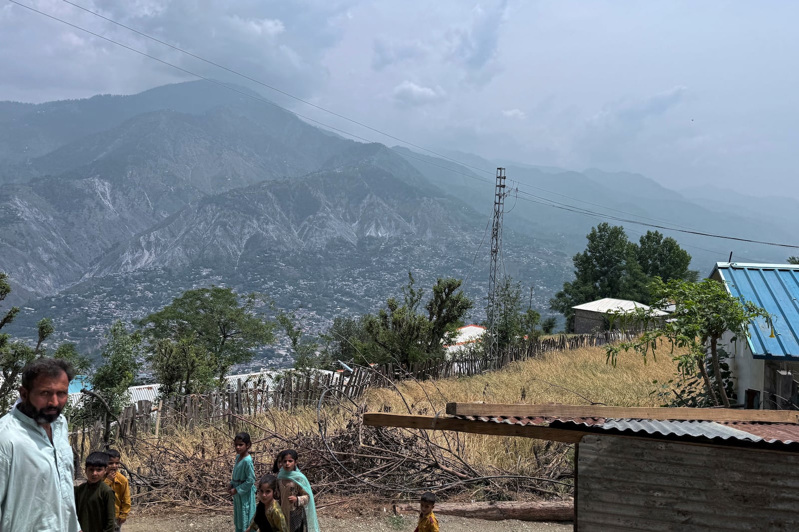 Villager walk on a dusty track during a government's organized trip for media to Bella Noor Shah, a mountainous village near Muzaffarabad, the capital of Pakistan administered Kashmir, Monday, May 5, 2025. (AP Photo/Muhammad Yousuf, Pool)