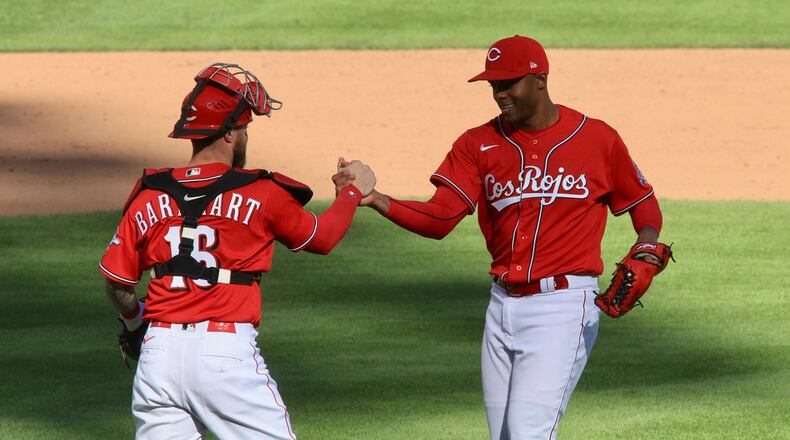 Reds catcher Tucker Barnhart and reliever Raisel Iglesias celebrate a victory against the White Sox on Sunday, Sept. 20, 2020, at Great American Ball Park in Cincinnati. David Jablonski/Staff