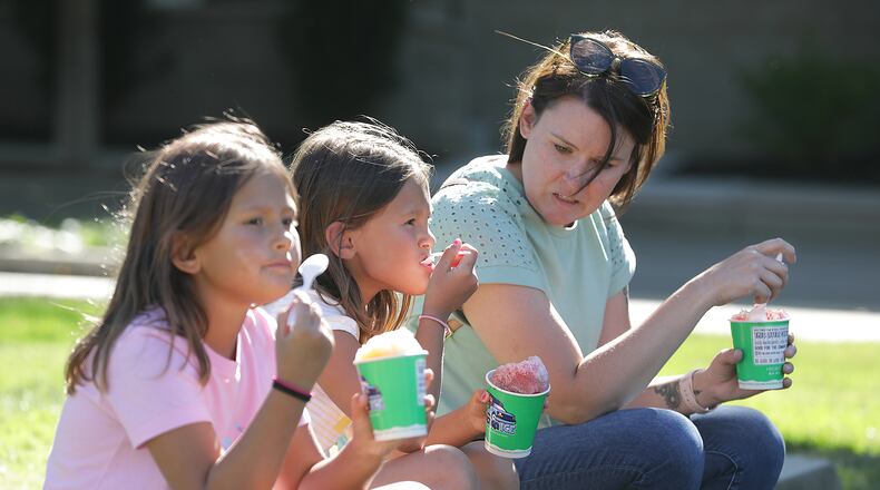 Sarah Cosby, right, enjoys some shaved ice with Penny and Phoebe Lama Thursday, June 23, 2022, during CommonsFest at National Road Commons Park in downtown Springfield. BILL LACKEY/STAFF