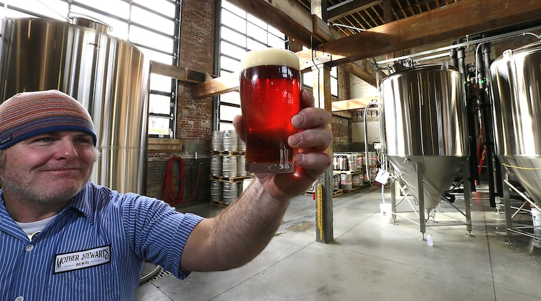 John Loftis holds up a glass of Mother Stewarts beer to the light Friday in their brew house. Mother Stewart’s has won a national ranking for being in the top new breweries last year. Bill Lackey/Staff