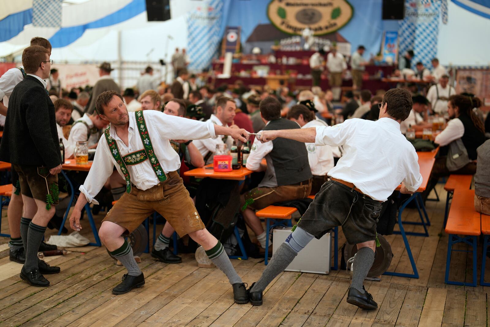 Competitors warm up for their bout while they try to pull the opponent over the table at the German Championships in Fingerhakeln or finger wrestling, in Pang, near Rosenheim, Germany, Sunday, April 27, 2025. (AP Photo/Matthias Schrader)