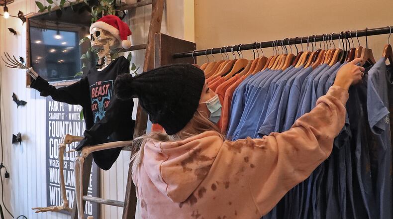 Kelcie Webster, manager of Champion City Guide & Supply, hangs some new shirts on a rack Wednesday. BILL LACKEY/STAFF