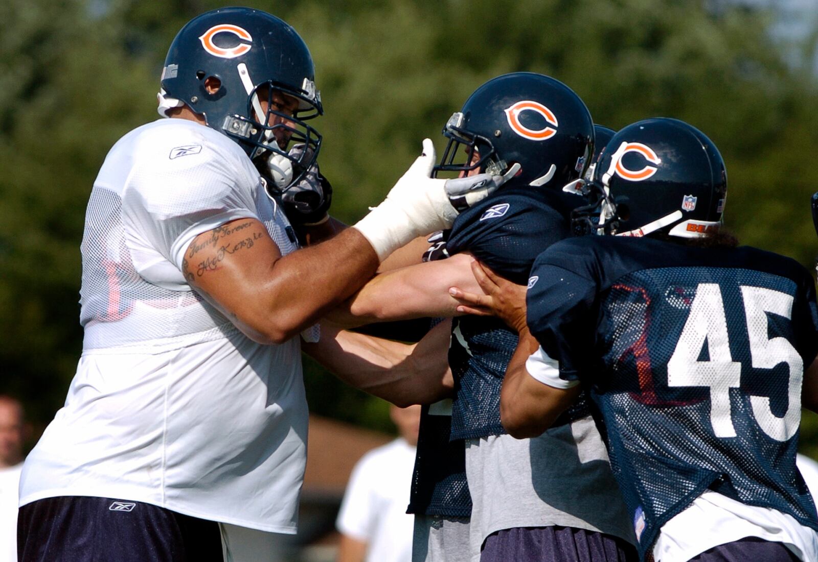 FILE - Chicago Bears' Aaron Gibson, left, and Cameron Worrell, center, get into a brief scuffle as Virgil Williams (45) tries to separate the teammates during training camp Saturday, July 31, 2004, in Bourbonnais, Ill. (AP Photo/Jeff Roberson, File)