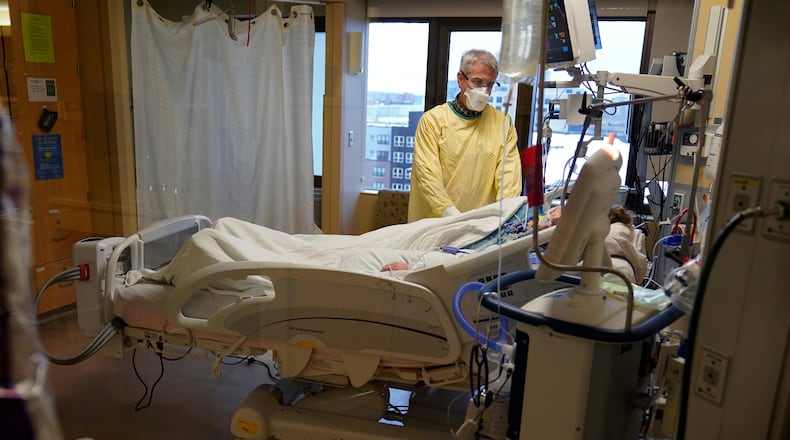 FILE - Steve Grove, a chaplain at Hennepin County Medical Center, prays in a COVID-19 patient's room, Dec. 10, 2021, in Minneapolis. (AP Photo/Charlie Neibergall, File)