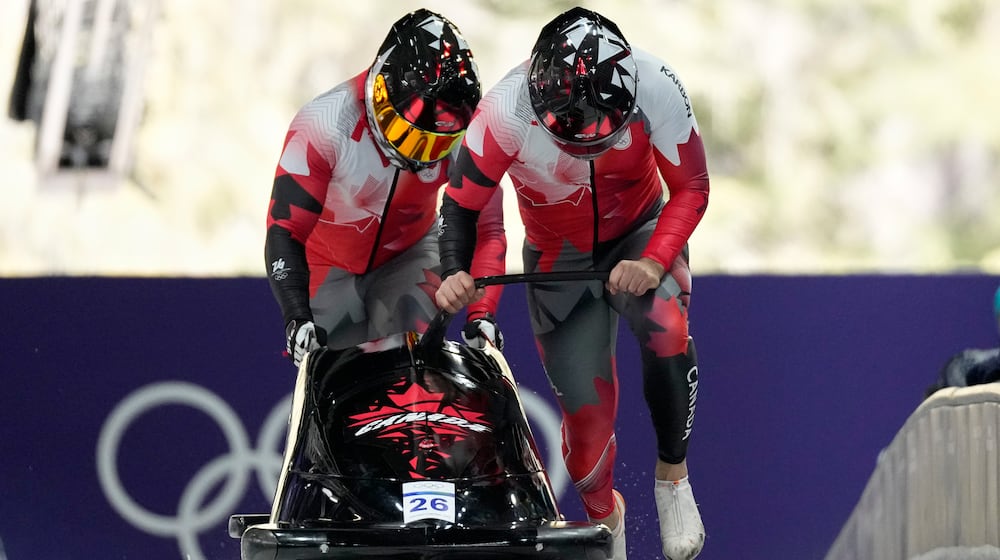 Canada's Taylor Austin, right, and Shaquille Murray-Lawrence start for a two man bobsled run at the 2026 Winter Olympics, in Cortina d'Ampezzo, Italy, Monday, Feb. 16, 2026. (AP Photo/Alessandra Tarantino)