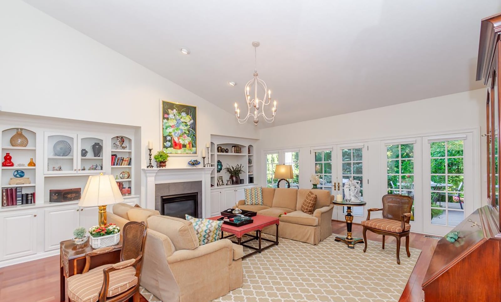 The living room has a vaulted ceiling, a wall of built in bookcases, a gas fireplace and exterior French doors opening to the back deck. CONTRIBUTED