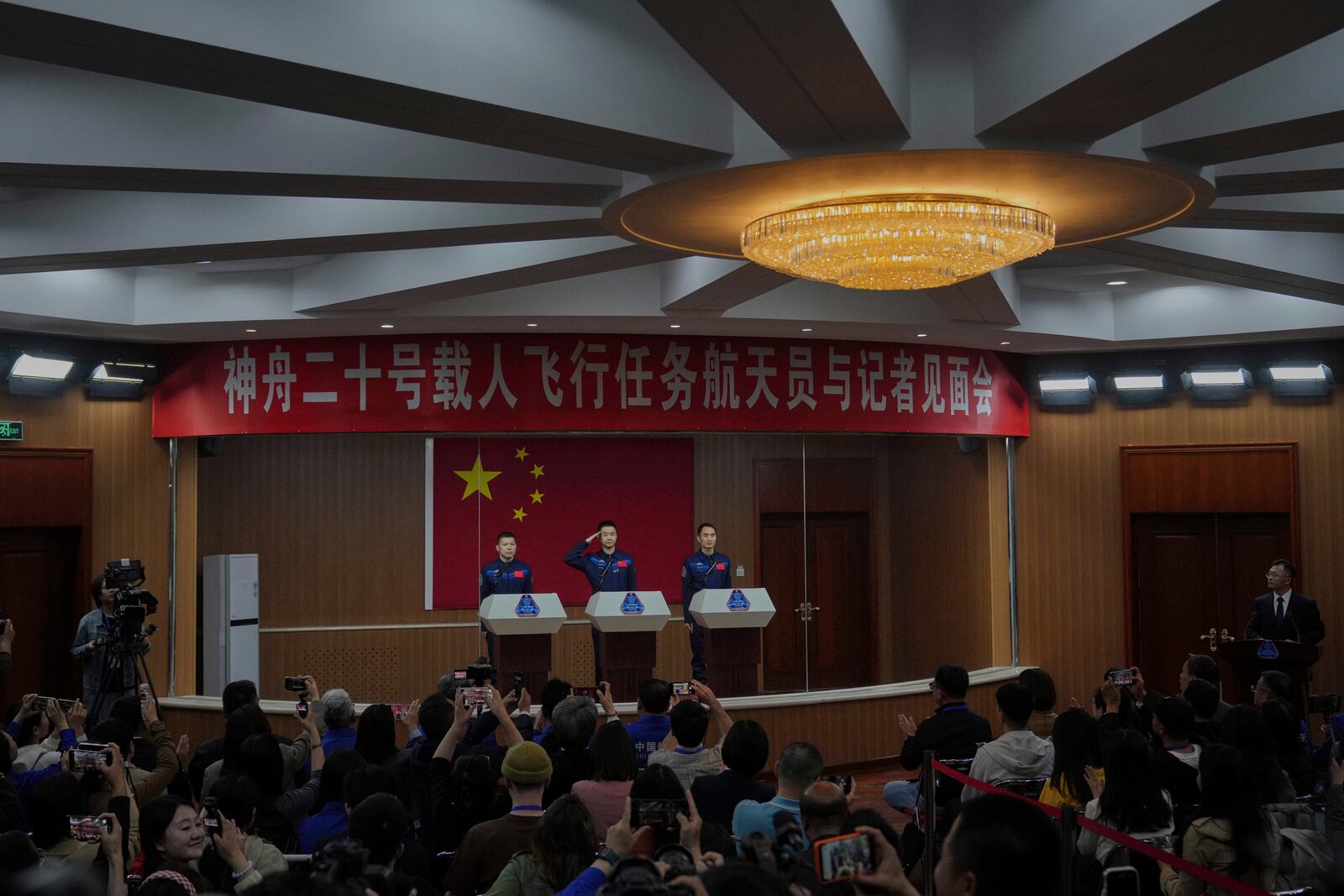 Astronaut for the upcoming Shenzhou 20 mission Chen Dong, center, salutes next to his comrades Wang Jie, left, and Chen Zhongrui during a meeting with the press at the Jiuquan Satellite Launch Center in northwest China, Wednesday, April 23, 2025. (AP Photo/Andy Wong)