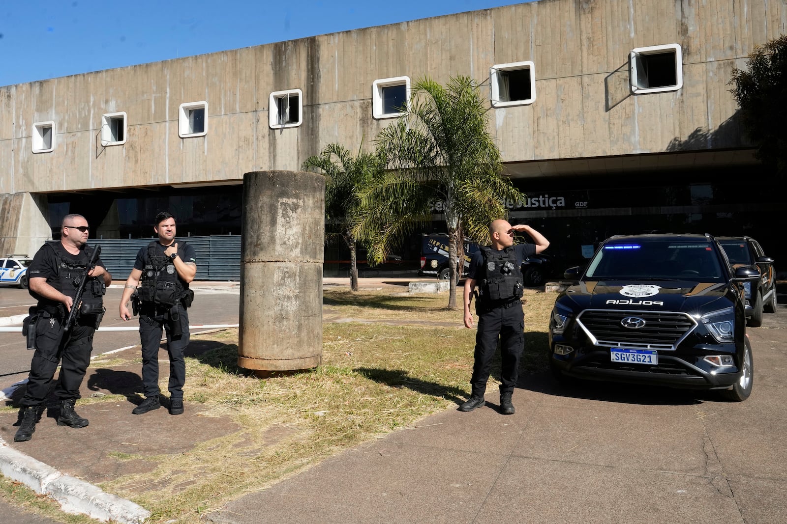Federal police officers stand at the the Secretariat of Penitentiary Administration office where Brazil's former President Jair Bolsonaro, who is on trial for allegedly attempting to stage a coup, after he arrived to be fitted with an electronic ankle monitor in Brasilia, Brazil, Friday, July 18, 2025. (AP Photo/Eraldo Peres)