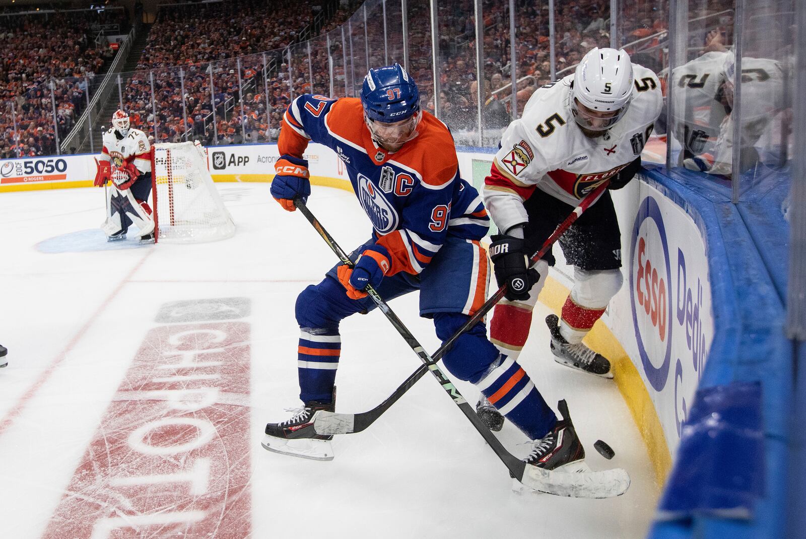 Florida Panthers' Aaron Ekblad (5) and Edmonton Oilers' Connor McDavid (97) battle for the puck during the first overtime period in Game 1 of the NHL hockey Stanley Cup final series in Edmonton, Alberta, Wednesday, June 4, 2025. (Jason Franson/The Canadian Press via AP)