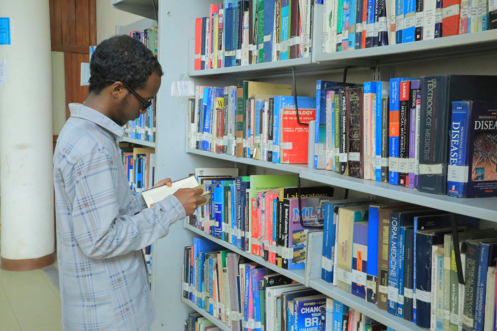 Yonas Nuguse, 21 years old, destined for Harvard University flicking through a book at Wemezeker National Library in Addis Ababa, Ethiopia Friday, May 30, 2025. (AP Photo/Amanuel Birhane)