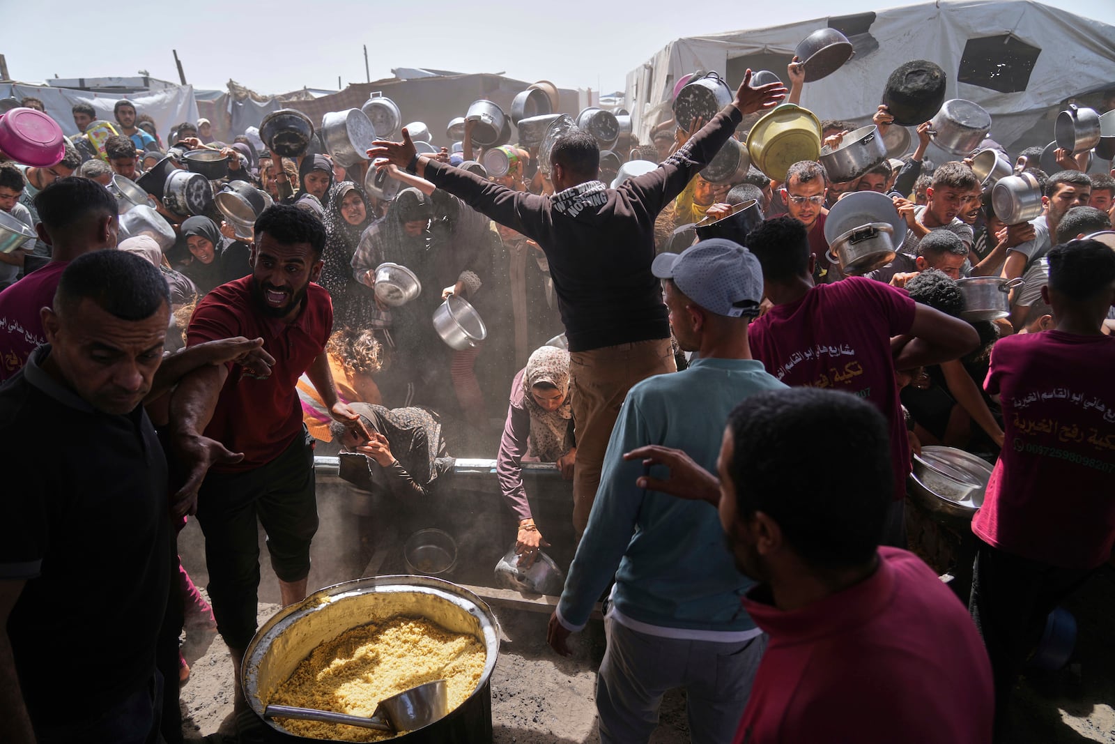 Palestinians struggle to get donated food at a community kitchen in Khan Younis, Gaza Strip, Friday, May 16, 2025. (AP Photo/Abdel Kareem Hana)