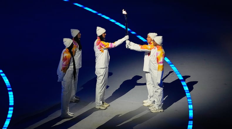 The Olympic torch is passed during the Olympic opening ceremony at the 2026 Winter Olympics, in Milan, Italy, Friday, Feb. 6, 2026. (AP Photo/Petr David Josek)