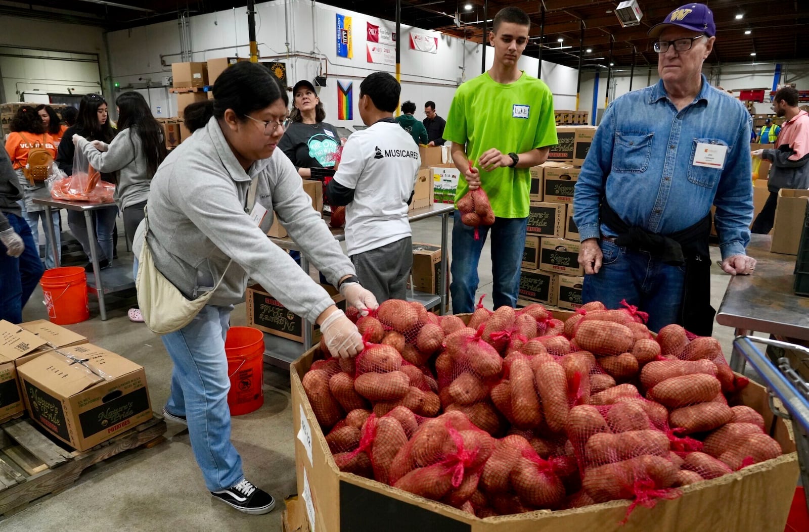 Volunteers pack produce at the Alameda County Community Food Bank in Alameda, Calif., on Friday, April 25, 2025. (AP Photo/Terry Chea)