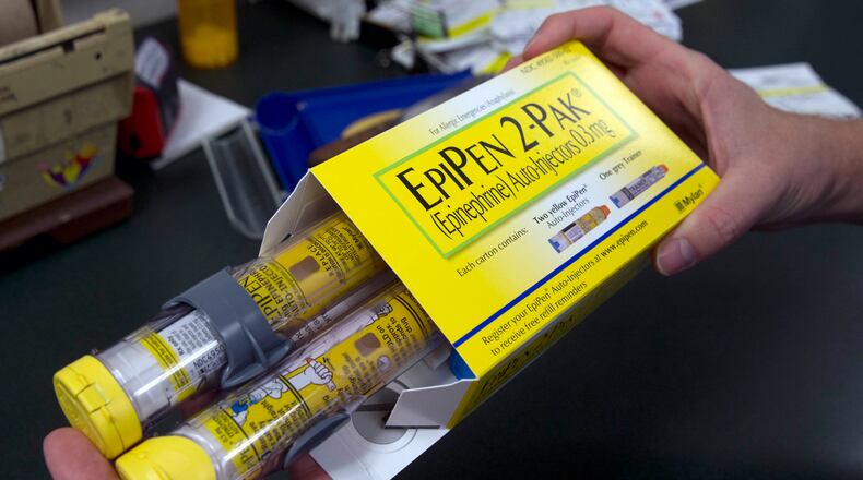 In this July 8, 2016, file photo, a pharmacist holds a package of EpiPens epinephrine auto-injector, a Mylan product, in Sacramento, Calif. (AP Photo/Rich Pedroncelli, File)
