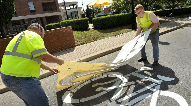 David Adkins, left, and Stephen Bowers from the City of Springfield touch up the bicycle crossing sign on South Fountain Avenue Thursday. Bill Lackey/Staff