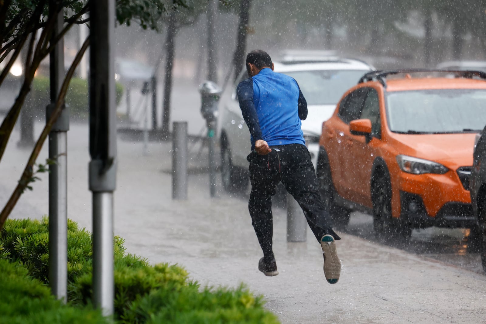 A man runs down the sidewalk along Commerce Street while heavy rain fall in downtown Dallas, Wednesday, April 30, 2025, and a flash flood warning was issued for parts of North Texas through this afternoon. (Elías Valverde II/The Dallas Morning News via AP)