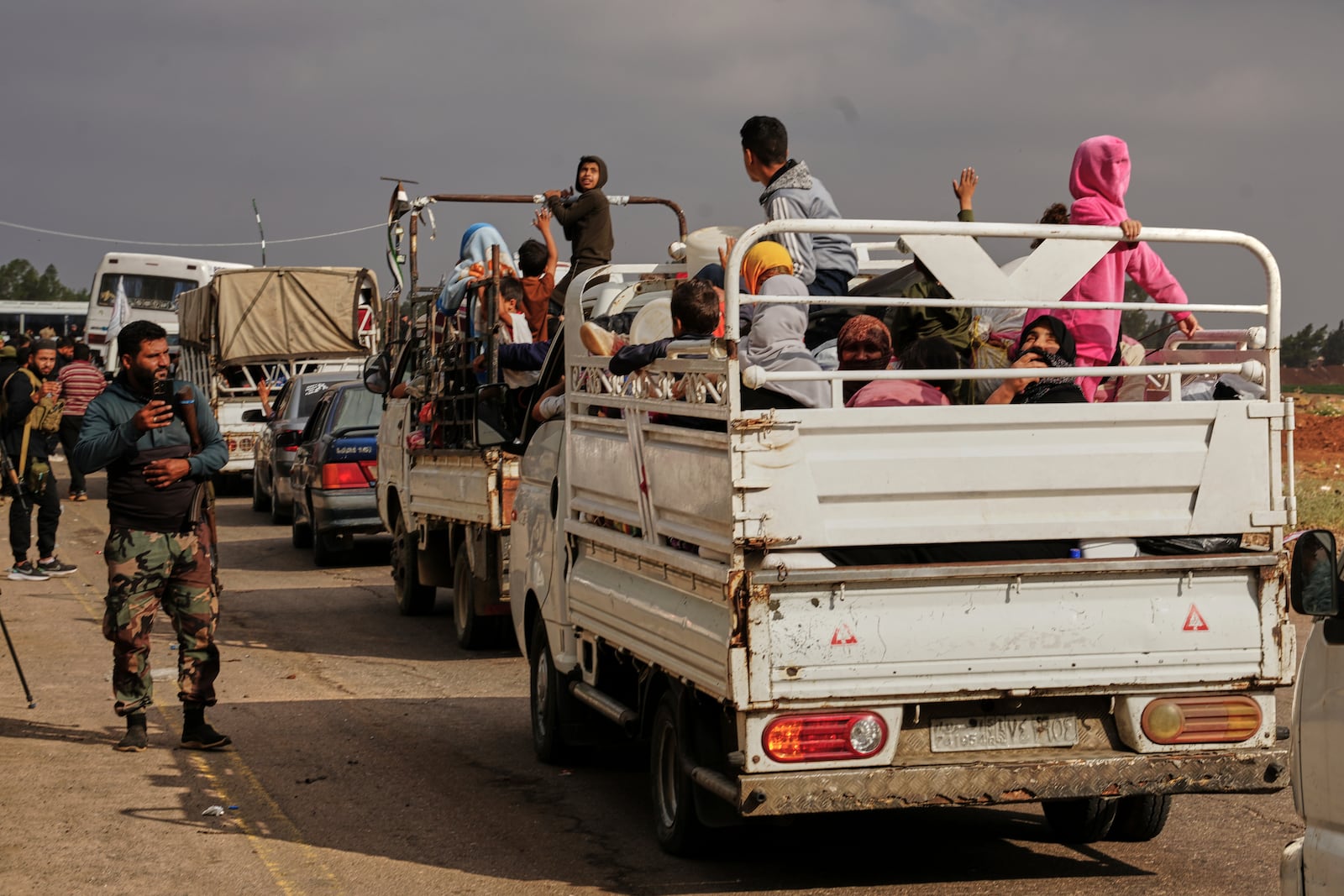 Syrian Bedouin families ride in the back of trucks carrying their belongings, in a convoy led by Red Crescent vehicles in Busra al-Harir, heading to Daraa after being evacuated from Sweida following more than a week of violent clashes, Monday, July 21, 2025. (AP Photo/Malek Khattab)