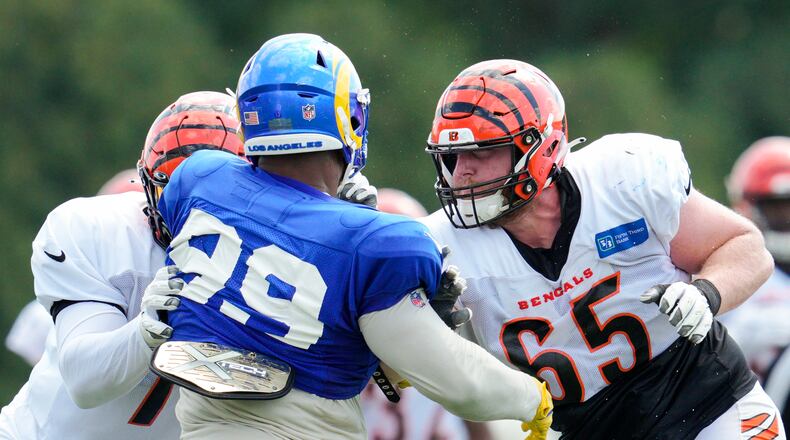 Cincinnati Bengals guard Alex Cappa (65) and offensive tackle La'el Collins, left, block Los Angeles Rams defensive tackle Aaron Donald (99) during a drill at the team's NFL football training facility, Wednesday, Aug. 24, 2022, in Cincinnati. (AP Photo/Jeff Dean)