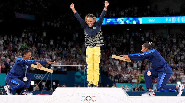 FILE - Silver medalist Simone Biles, of the United States, left, and bronze medalist Jordan Chiles, of the United States, right, bow to gold medalist Rebeca Andrade, of Brazil, during the medal ceremony for the women's artistic gymnastics individual floor finals at Bercy Arena at the 2024 Summer Olympics, Aug. 5, 2024, in Paris, France. (AP Photo/Abbie Parr, File)