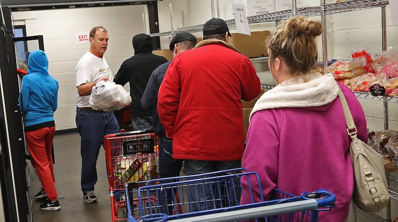 Nick Kneisley, a volunteer at the Second Harvest Food Bank, helps people in the food pantry Thursday, Nov. 29, 2018. BILL LACKEY/STAFF