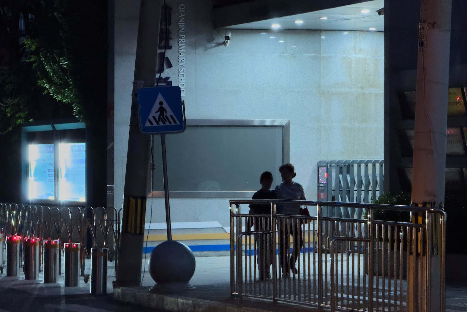 A woman and a child walk by an entrance gate of Qianjin primary school after a driver hit and injured several pedestrians outside the school in the northwestern Haidian district, in Beijing on May 15, 2025. (AP Photo/Andy Wong)