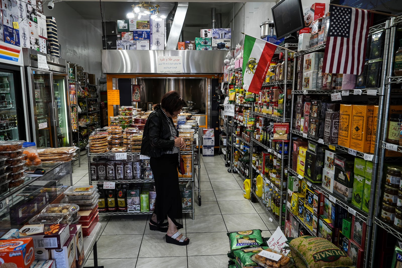 A woman shops at a grocery store decorated with American and Iranian flags in the "Tehrangeles" neighborhood of Los Angeles Tuesday, June 24, 2025. (AP Photo/Jae C. Hong)