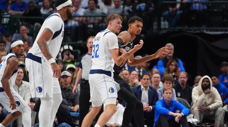 San Antonio Spurs forward Victor Wembanyama, right, is defended by Dallas Mavericks forward Cooper Flagg (32) as forward Anthony Davis, second from left, looks on during the second half of an NBA basketball game in Dallas, Wednesday, Oct. 22, 2025. (AP Photo/LM Otero)