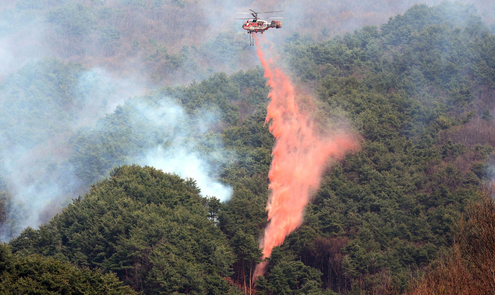 A Korea Forest Service helicopter dumps fire retardant on a wildfire in Sancheong, South Korea, Tuesday, March 25, 2025. (Kim Dong-min/Yonhap via AP)