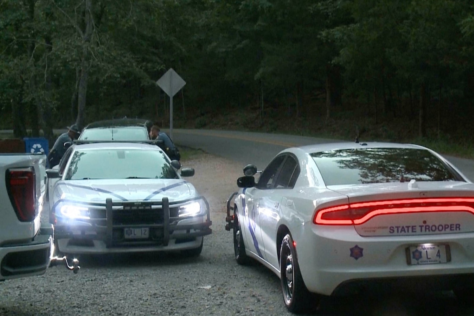 In this image made from video taken on Saturday, July 26, 2025, provided by KHBS/KHOG, Law enforcement officers investigate the deaths of a couple who were attacked while on a wooded walking trail with their two young daughters at Devil's Den State Park in West Fort, Ark. (KHBS/KHOG via AP)