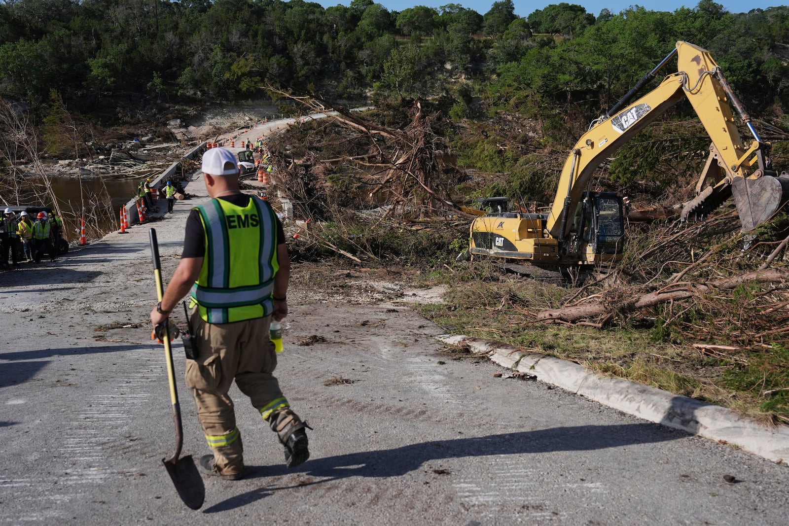 Crews work on the Cade Loop Bridge to clear debris following flooding, Thursday, July 10, 2025, in Ingram, Texas. (AP Photo/Joshua A. Bickel)