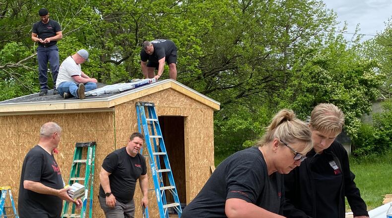 A group of Gordon Food Services volunteers putting on a roof of the shed on Katara Woods' property on West Perrin Avenue, a home that was dedicated to her and her family at the beginning of June. Contributed