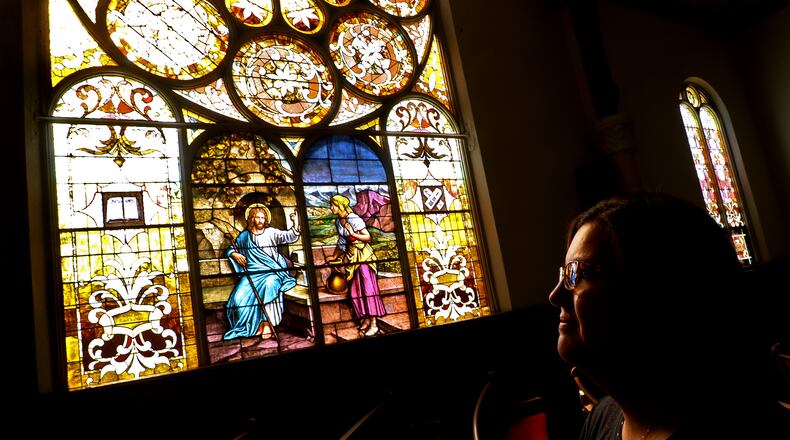 Nikki Crist, church secretary at St John's Evangelical Lutheran Church, looks over the stained glass windows in the church's sanctuary Tuesday. This year marks the 175th anniversary of the church. BILL LACKEY