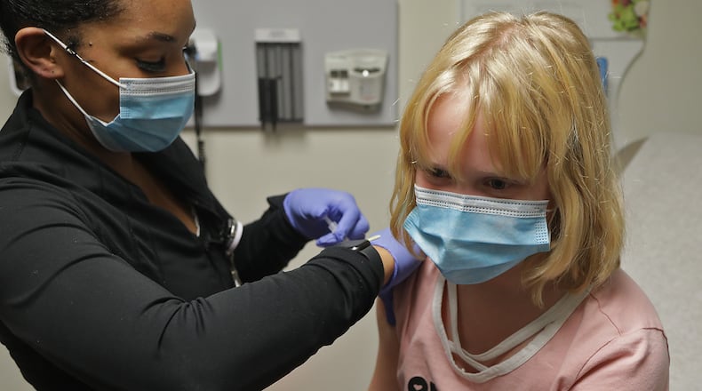 School districts in Clark and Champaign Counties have reported 150 coronavirus cases. Here, Lily True, 9, gets her COVID-19 vaccine shot at the Rocking Horse Center. BILL LACKEY/STAFF