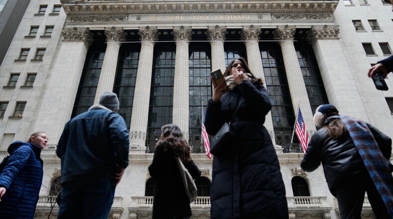 Pedestrians mill about outside the New York Stock Exchange in New York, Friday, March 6, 2026. (AP Photo/Seth Wenig)