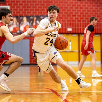 Emmanuel Christian Academy senior Nate Hudson drives past Twin Valley South junior Lucas Barlow boys basketball team beat Twin Valley South in a Division VI district semifinal game on Monday, March 2, 2026 at Troy High School. The Lions won 73-50. MICHAEL COOPER / STAFF