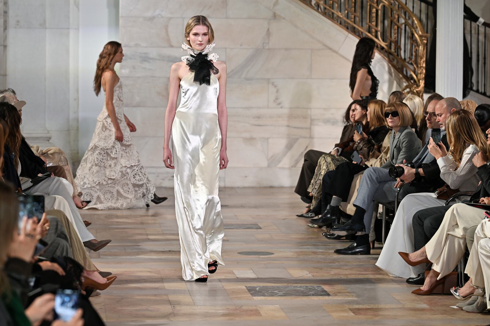 A model walks the runway as Anna Wintour, right, looks on at the Ralph Lauren Fall 2025 presentation on Thursday, April 17, 2025, in New York. (Photo by Evan Agostini/Invision/AP)