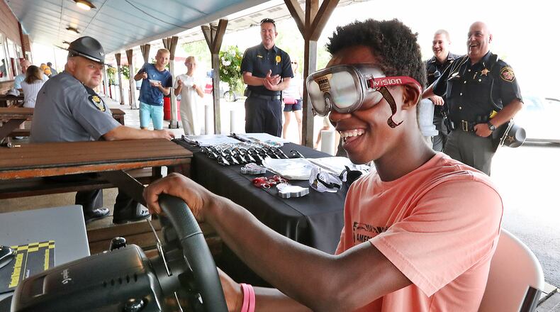 Pierre Bowman, 14, tries to operate a driving simulator with a pair of Fatal Vision, drunk goggles, on Friday during the Drive Sober or Get Pulled Over campaign kickoff at Youngs Jersey Dairy. BILL LACKEY/STAFF