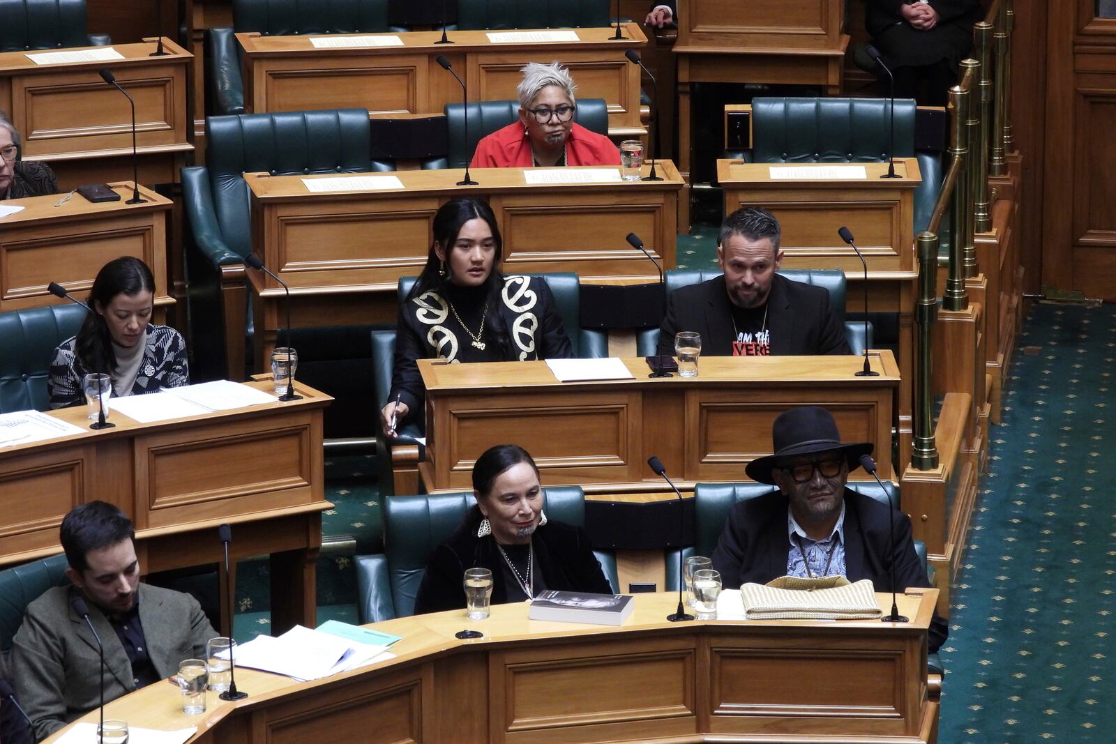 New Zealand lawmakers, Hana-Rāwhiti Maipi-Clarke, center at second row, Debbie Ngarewa-Packer, center in front row, and Rawiri Waititi, bottom right, who received lengthy suspensions from Parliament for a protest haka they performed last November, watch as other legislators debate their proposed bans in Wellington, New Zealand Thursday, June 5, 2025. (AP Photo/Charlotte Graham-McLay)