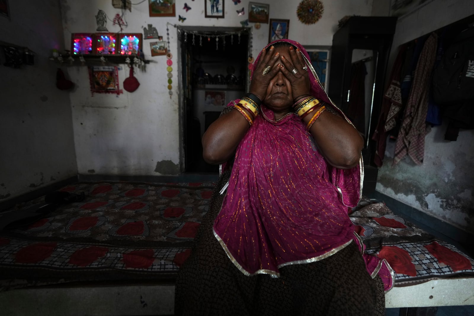Shantaben Vanzara, wearing a wristwatch-style health monitor to study how heat affects vulnerable communities, wipes her face inside her house in Ahmedabad, India, Wednesday, April 2, 2025. (AP Photo/Ajit Solanki)