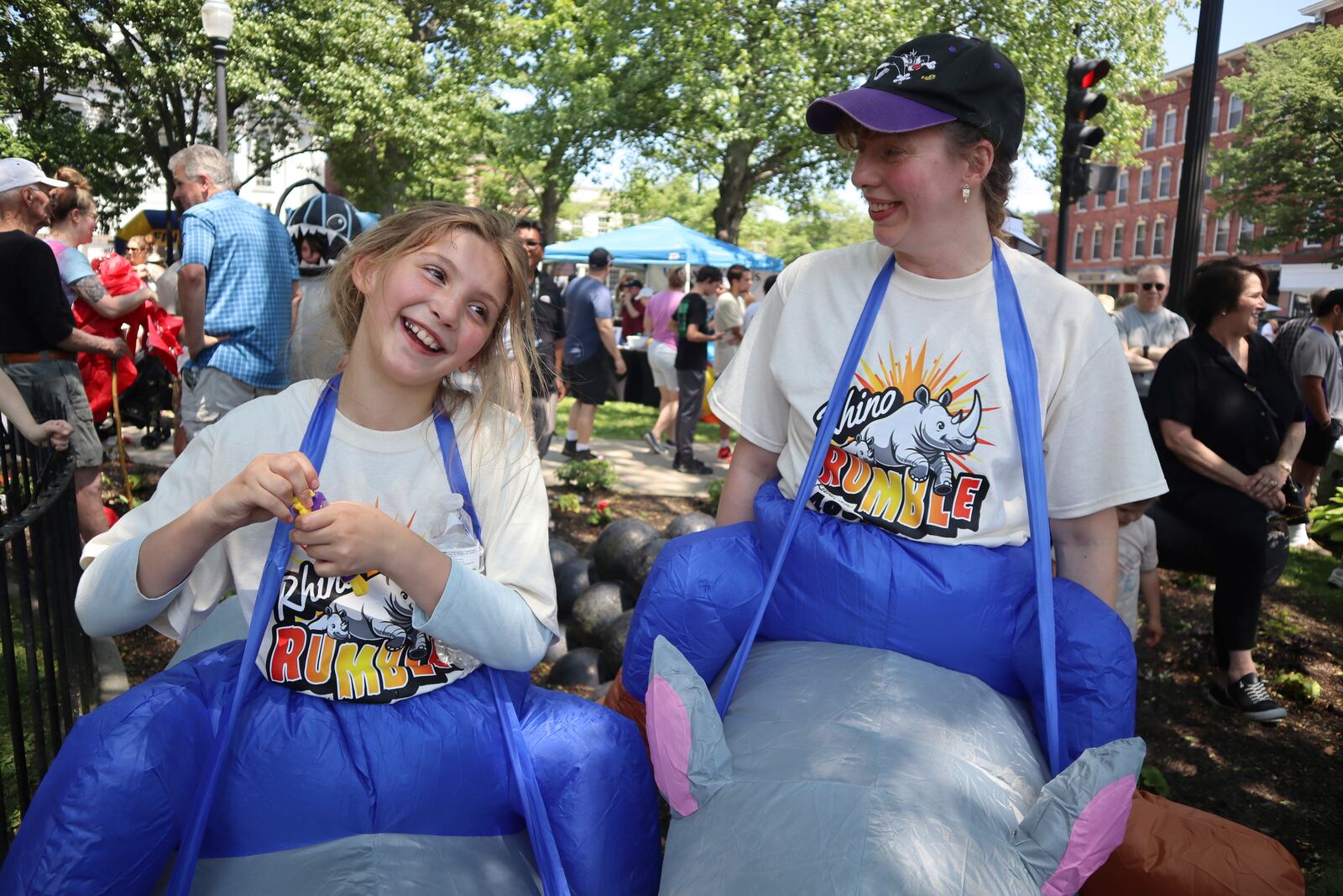 Juniper Thurston, right, and 9-year-old daughter Madison Christgau celebrate the 30th anniversary of the film 'Jumanji' by wearing inflatable rhino costumes in downtown Keene, N.H. on Saturday, June 21, 2025. (AP Photo/Leah Willingham)