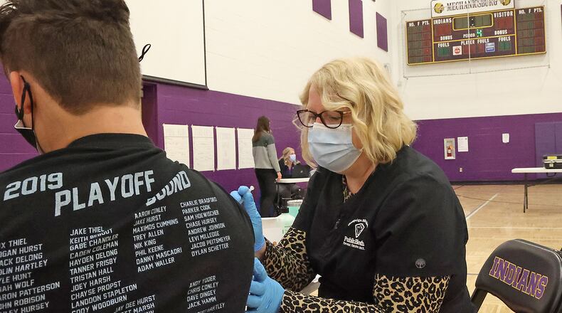 Mechanicsburg schools will now require short term masking for certain classes due to positive COVID-19 cases. Here, Hope Stickley, a nurse from the Champaign County Health Department, gave a student the COVID vaccine earlier this year during a COVID clinic in one of Mechanicsburg High School's gymnasiums. BILL LACKEY/STAFF