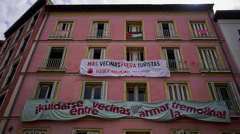 FILE - Banners against tourist holiday rentals hang on the facade of a building in downtown Madrid, Spain, Tuesday, June 3, 2025. The writing in Spanish reads: "More neighbors, fewer tourists. Tenant power," and "Looking out for each other as neighbors, stirring things up." (AP Photo/Manu Fernandez)