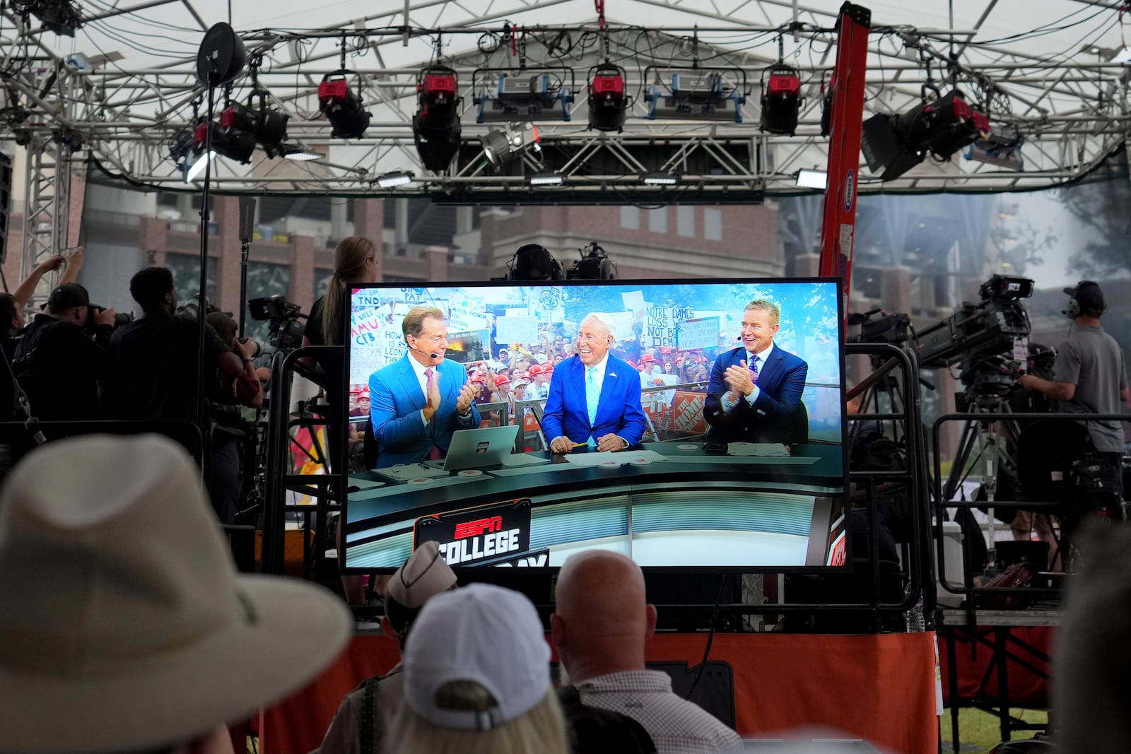 From left, ESPN football analyst Nick Saban, Lee Corso and Kirk Herbstreit can be seen on a monitor outside of Kyle Field during the start of ESPN College Game Day on Aug. 31, 2024, in College Station, Texas. (AP Photo/Sam Craft, FILE)