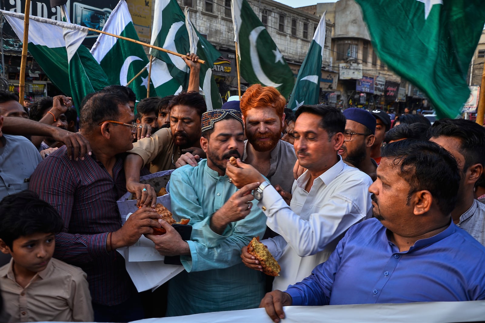People share cake as they celebrates following India and Pakistan have reached a ceasefire deal, during a demonstration, in Hyderabad, Pakistan, Saturday, May 10, 2025. (AP Photo/Pervez Masih)
