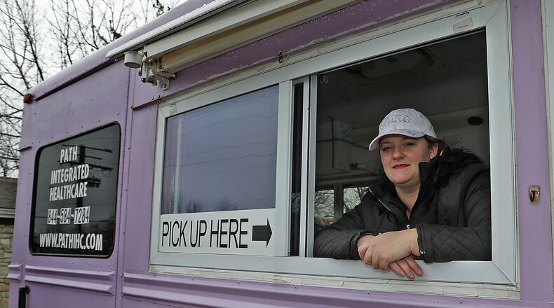 Mandy Gabbert, from Path Integrated Healthcare, in the purple bus they serve free dinners out of for homeless and hungry people. BILL LACKEY/STAFF
