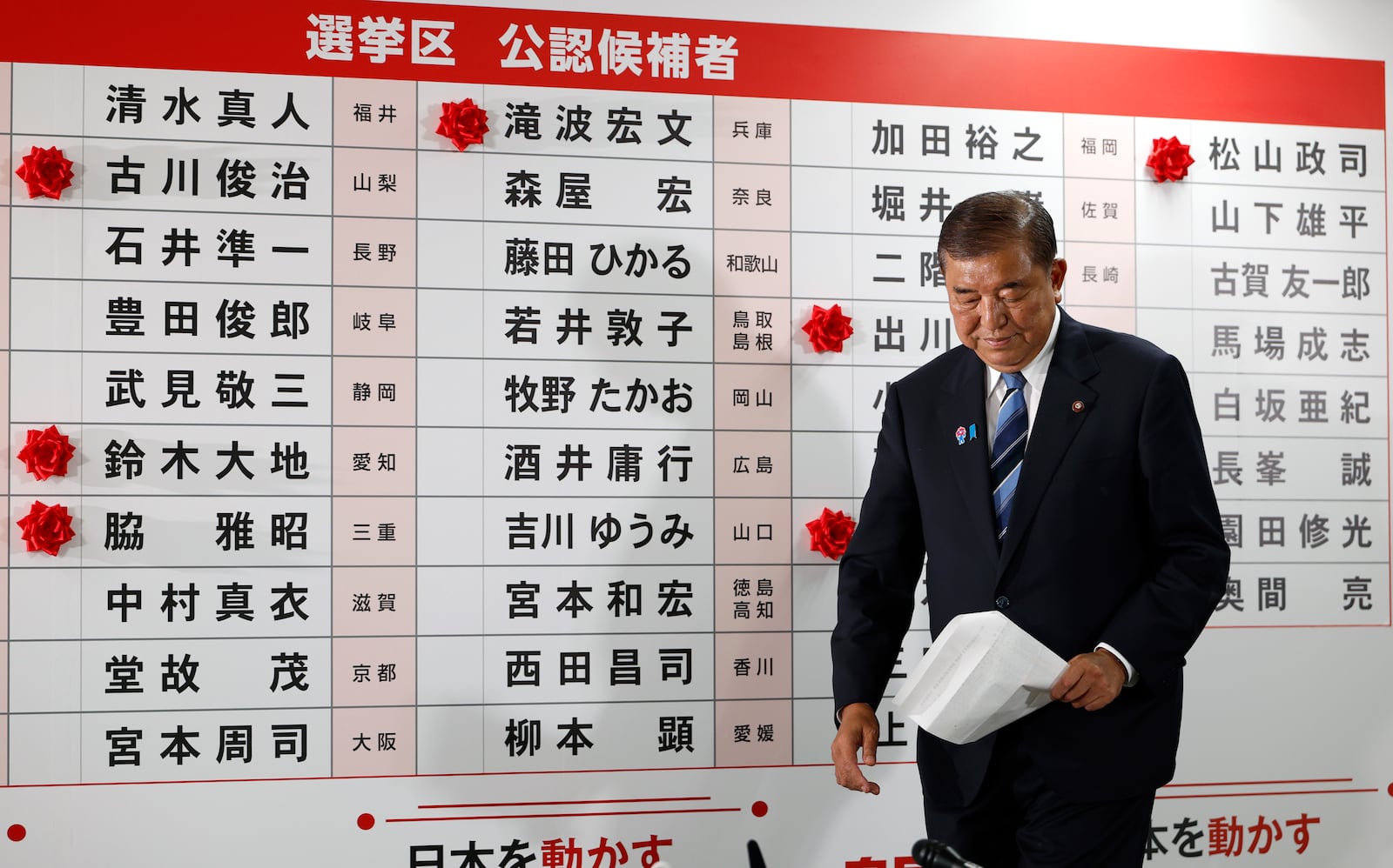 Shigeru Ishiba, Japan's Prime Minister and president of the ruling Liberal Democratic Party (LDP), walks before a board with few red paper roses showing elected candidate at the LDP headquarters in Tokyo, Sunday, July 20, 2025. (Franck Robichon, Pool Photo via AP)