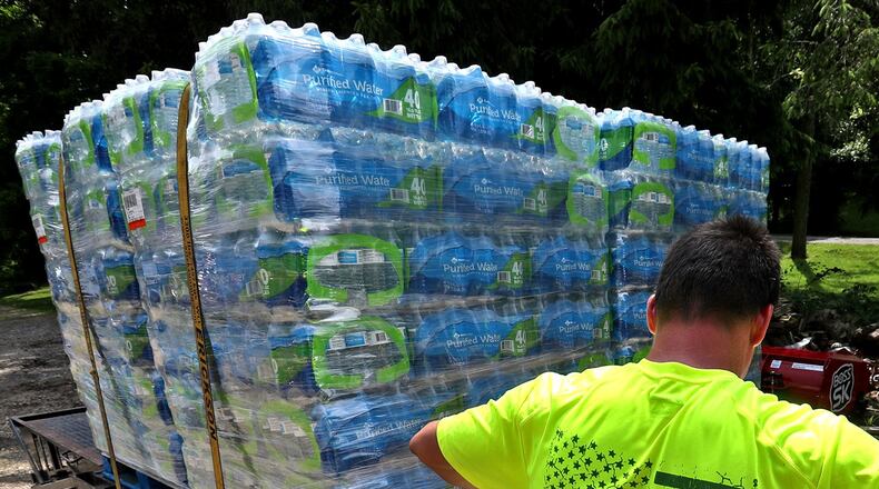 James Coburn, of Coburn Concrete in New Carlisle, loads supplies on a trailer already carrying thousands of bottles of donated drinking water for the Dayton tornado victims Friday. Coburn said the flag on the back of his shirt reminds him that we’re all Americans and we should help each other. BILL LACKEY/STAFF