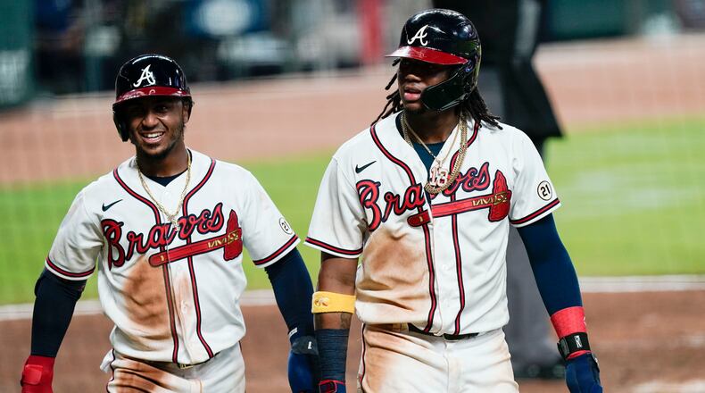 Atlanta Braves' Ozzie Albies, left and Ronald Acuna Jr. walk to dugout after scoring during the fourth inning the team's a baseball game against the Miami Marlins Wednesday, Sept. 9, 2020, in Atlanta. (AP Photo/Brynn Anderson)