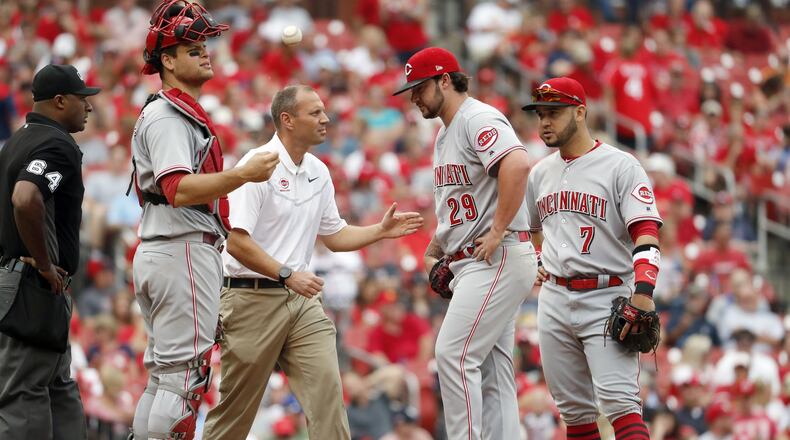 Cincinnati Reds starting pitcher Brandon Finnegan (29) is checked on by a trainer as teammates Devin Mesoraco, left, and Eugenio Suarez (7) stand by during the fourth inning of a baseball game against the St. Louis Cardinals Monday, June 26, 2017, in St. Louis. Finnegan left the game. (AP Photo/Jeff Roberson)
