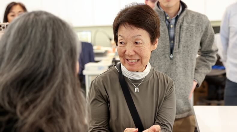 Karen Okawa, Japanese Church of Christ member and time capsule committee member, reacts as she holds a heavy lid that was used on the Japanese Church of Christ's 100-year-old time capsule at the University of Utah Marriott Library Preservation Department in Salt Lake City, Monday, Oct. 20, 2025. (Kristin Murphy/The Deseret News via AP)